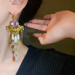 Détail de boucles d'oreilles style palais vintage avec pierre violette et perles