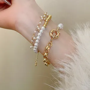 Élégant ensemble de trois bracelets en chaîne dorée et perles blanches sur un poignet
