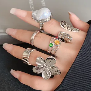 Close-up of irregular silver metal ring set with floral and pearl designs on a hand