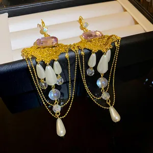 Vue détaillée de boucles d'oreilles vintage style palais avec pampilles, pierres et perles.