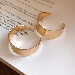 Close-up detail of polished gold-finished vintage C-shaped hoop earrings on a book