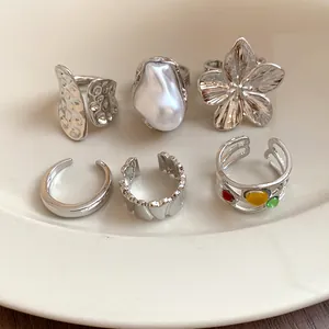 Close-up detail of a six-piece silver metallic open ring set with various textures.
