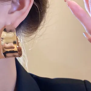 Close-up of elegant gold-finished C-shaped hoop earrings on an ear for a chic look