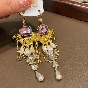 Détail de boucles d'oreilles vintage style palais français avec gemmes violettes et perles.