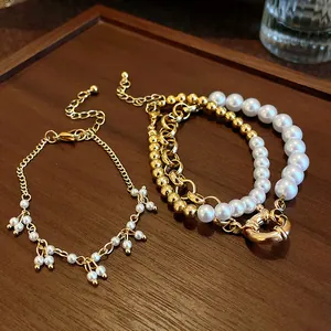 Détail de bracelets en perles dorées vintage avec fermoir TO et chaînes à plusieurs rangs.