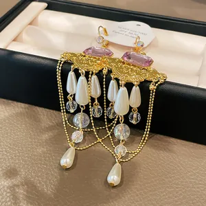 Gros plan de boucles d'oreilles vintage françaises avec gemmes roses et perles en boîte