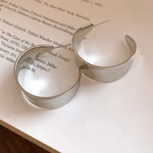 Detailed macro shot of vintage minimalist silver C-shaped hoop earrings on a book page