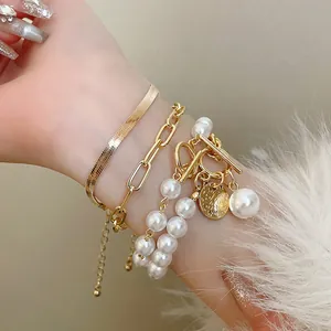 Détail d'un ensemble de bracelets dorés vintage avec des perles fantaisie et une chaîne serpent