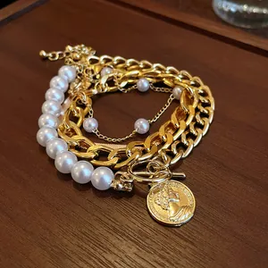 Gros plan sur un bracelet à chaînes dorées et perles avec un pendentif pièce vintage