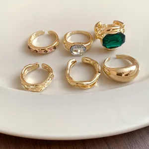 Macro view of golden geometric open ring set with emerald and sparkling rhinestone details