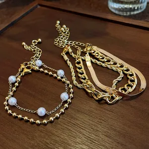Gros plan de bracelets dorés vintage avec perles et chaînes en os de serpent.
