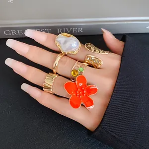 Close-up of bohemian gold geometric ring set featuring orange flower and pearl accents