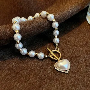 Gros plan d'un élégant bracelet de perles blanches avec fermoir OT doré et pendentif coeur