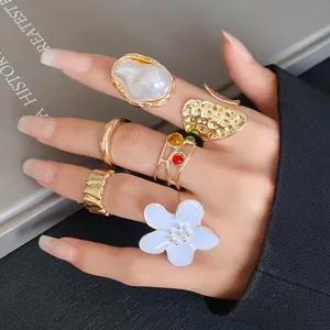 Detailed shot of a vintage gold-plated ring set featuring baroque pearl and enamel flower