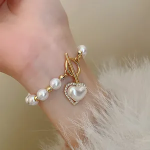 Gros plan d'un bracelet de perles vintage avec fermoir OT et pendentif cœur diamanté