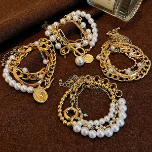 Gros plan de bracelets multicouches vintage en perles et chaînes dorées avec fermoirs TO