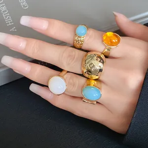 Macro view of chunky gold-toned geometric ring set with colorful stones on hand
