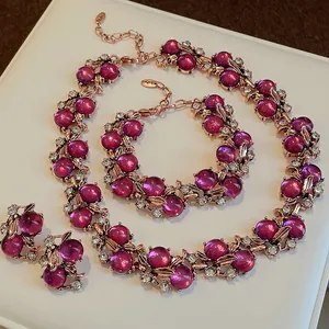 Set di gioielli vintage con perle magenta e accenti di fiori e foglie in oro rosa