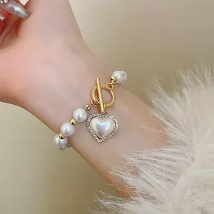 Détail d'un bracelet de perles élégant avec pendentif cœur doré et fermoir à bascule