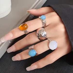 Detailed view of fashionable geometric metal rings set with colorful stones on a hand