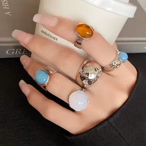 Close-up of stylish irregular metallic open ring set with colorful stones on hand model