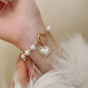 Gros plan d'un élégant bracelet en perles avec pendentif cœur et fermoir TO doré