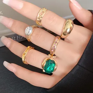Detailed close-up of a diverse gold-toned ring set with emerald and crystal accents.