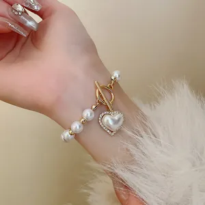 Gros plan d'un bracelet en perles vintage avec pendentif cœur et fermoir OT doré