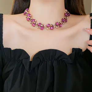 Primo piano di una collana floreale vintage con perle viola indossata da una modella in nero