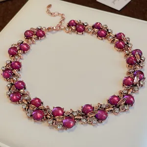 Dettaglio della collana con perle magenta, foglie in oro rosa e accenti di strass