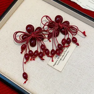Eleganti orecchini a perno in resina rosso scuro con fiocco e nappa dal finish vintage