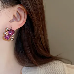 Elegante orecchino vintage in strass viola con design a fiore e foglia su modella