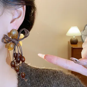 Eleganti orecchini a perno con fiocco e nappe in resina marrone, stile artigianale, autunnali