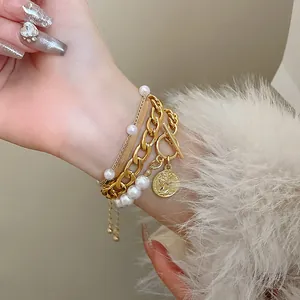 Gros plan d'un bracelet multicouche en perles et chaîne dorée avec pendentif pièce