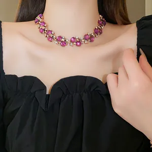 Dettaglio ravvicinato di una collana vintage con gemme viola e fiori d'oro
