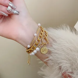 Gros plan d'un bracelet doré multicouche avec perles et pendentif de pièce de monnaie.