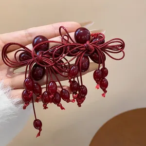 Vista dettagliata di eleganti orecchini a nappa con fiocco in perle di resina rosso scuro