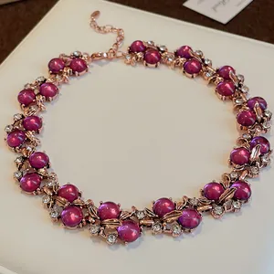 Dettaglio della collana vintage in oro rosa con perle viola e design a foglia