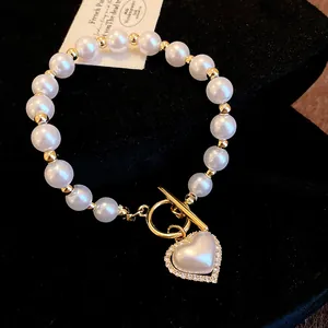 Gros plan détaillé d'un bracelet de perles vintage avec un pendentif en forme de cœur et fermoir T