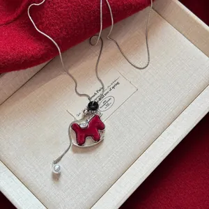 Close-up of a red flocked rocking horse sweater chain on a textured jewelry box background.
