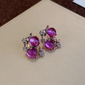 Vista dettagliata di orecchini vintage a bacca viola con strass e foglie d'oro rosa