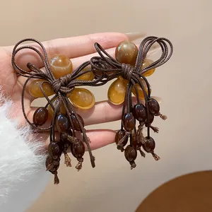 Dettaglio di orecchini a fiore in resina con nappe di perle marroni per l'inverno
