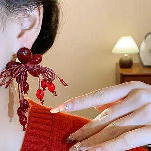 Primo piano di eleganti orecchini a fiore rosso in resina con fiocco e nappine.