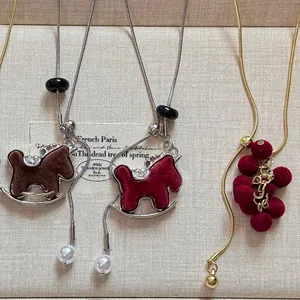 Detail of stylish flocked rocking horse and grape necklaces with adjustable snake chains.