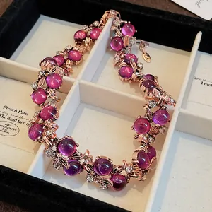 Dettaglio della collana vintage in oro rosa con fiori, foglie e pietre viola