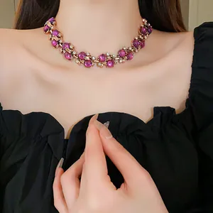 Primo piano di una collana vintage di perle viola con design a foglie dorate e cristalli