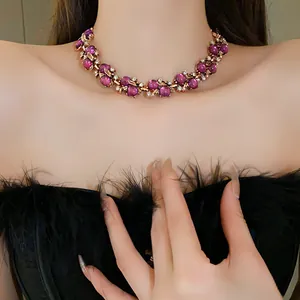 Primo piano di una collana vintage con perle viola e dettagli di foglie e strass