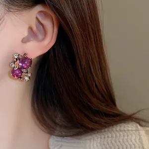 Dettaglio ravvicinato di orecchini vintage a bacca viola con foglie e piccoli strass