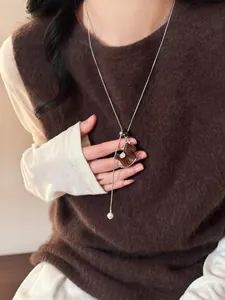 Elegant flocked animal pendant sweater necklace with a pearl tassel on brown knitwear