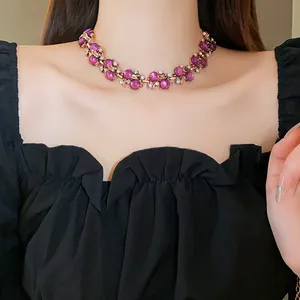 Primo piano di una collana vintage con perle viola e dettagli floreali dorati su una modella.